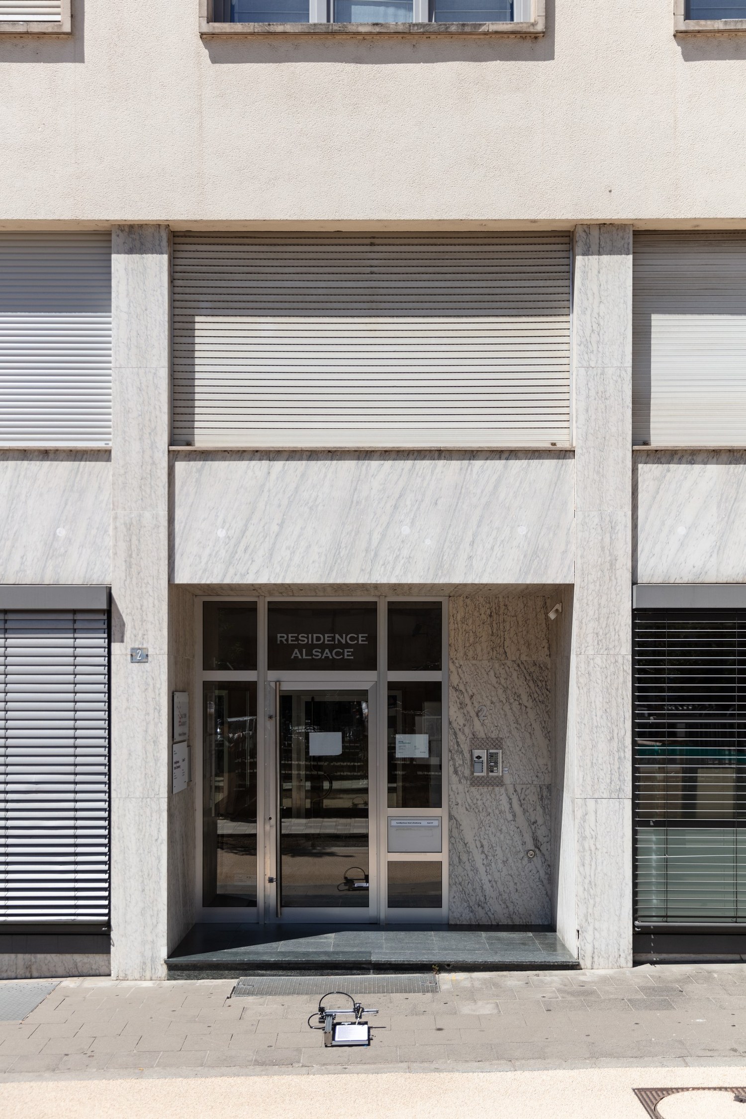 The entrance of 2, place de Strasbourg, an apartment block where the register lists 566 live companies at one entrance. The plotter sits on the pavement in front of the door, drawing the sheet for this address.